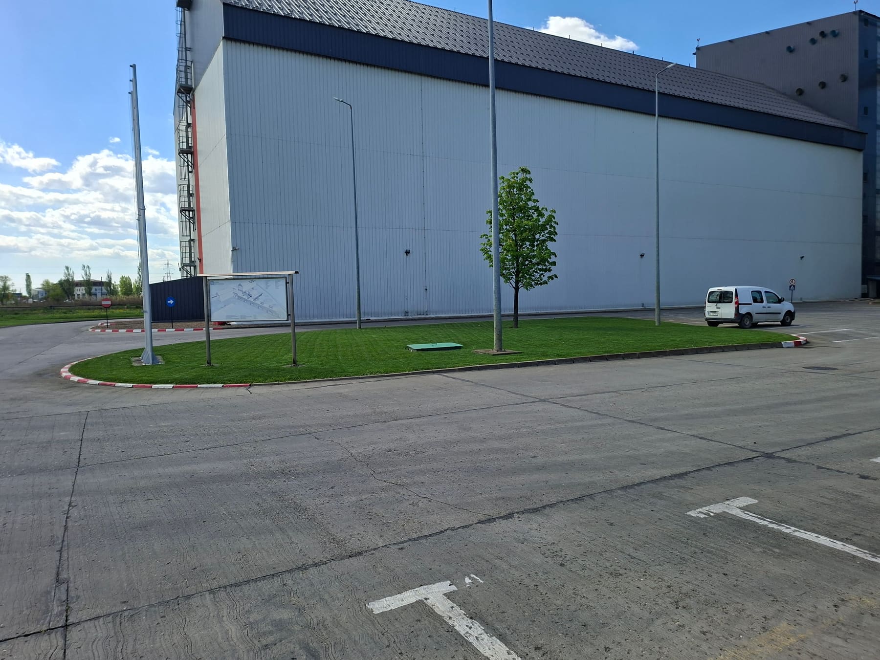 Gazon întreținut pe o zonă verde de lângă o hală industrială